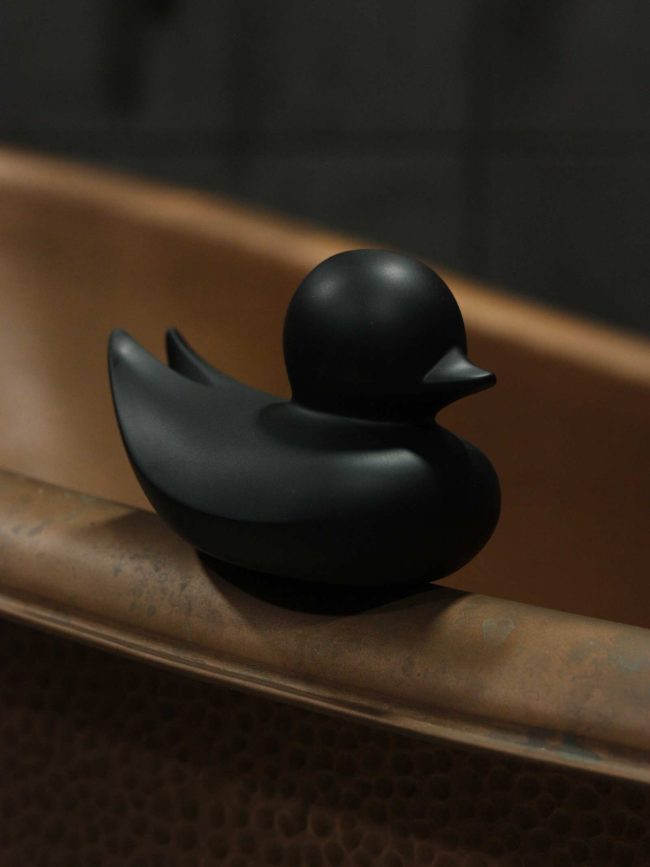 Black Kaamos rubber duck on copper bath tub